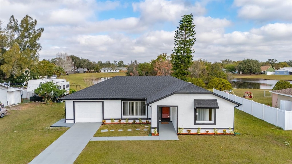 view of front of home with a garage, a front lawn, and a water view