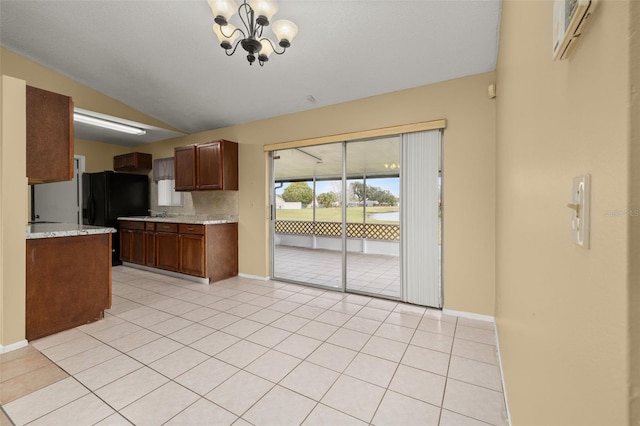 kitchen featuring vaulted ceiling, black refrigerator, light tile patterned floors, a notable chandelier, and light stone countertops