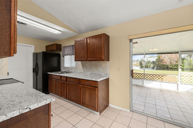 kitchen featuring light tile patterned flooring, plenty of natural light, black fridge with ice dispenser, and backsplash