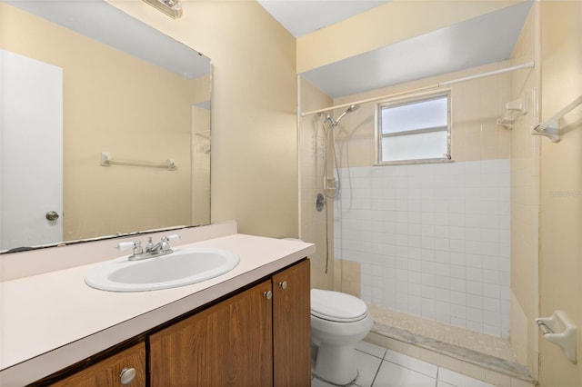 bathroom featuring vanity, tile patterned floors, toilet, and tiled shower