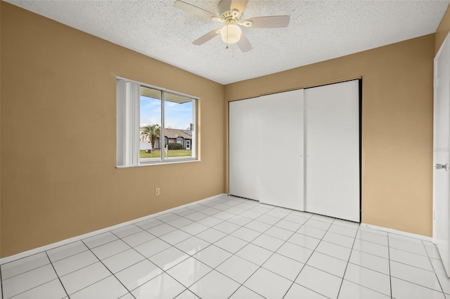 unfurnished bedroom featuring light tile patterned flooring, ceiling fan, a closet, and a textured ceiling