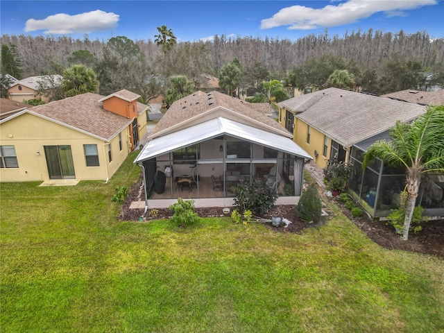 rear view of house with a yard and a sunroom