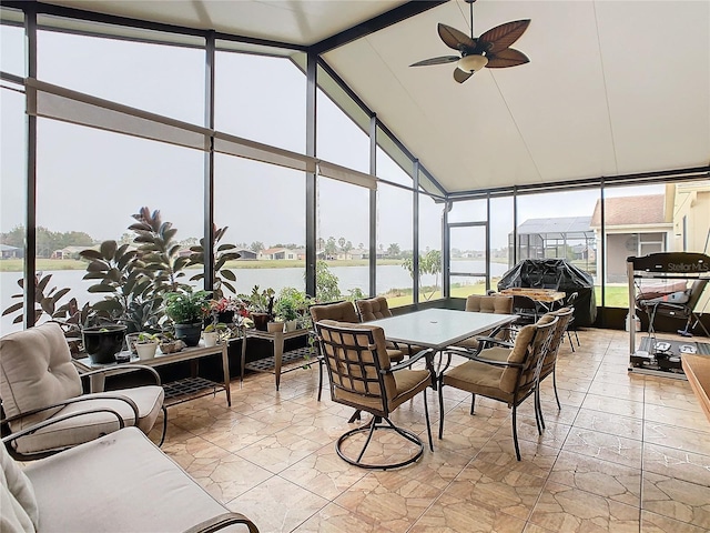 sunroom with plenty of natural light, lofted ceiling with beams, ceiling fan, and a water view