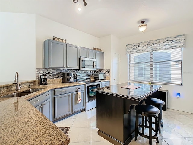 kitchen featuring tasteful backsplash, appliances with stainless steel finishes, a kitchen breakfast bar, and sink