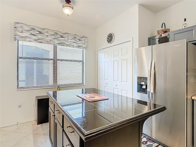 kitchen with a kitchen island, light tile patterned floors, and stainless steel fridge with ice dispenser