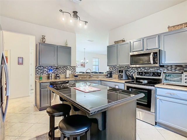 kitchen with a kitchen bar, light tile patterned floors, a kitchen island, and appliances with stainless steel finishes