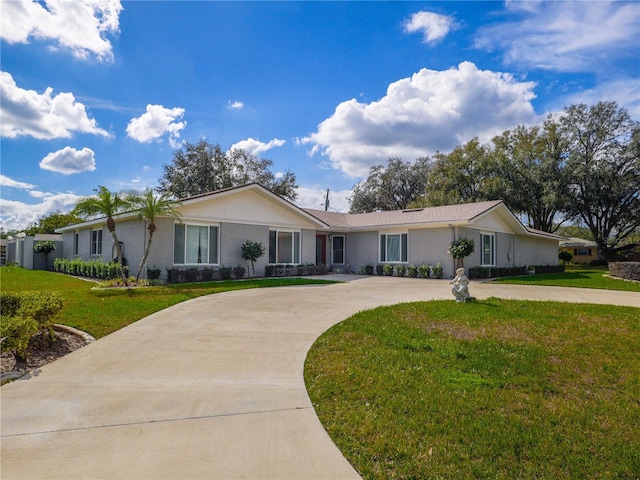 ranch-style house with concrete driveway and a front lawn