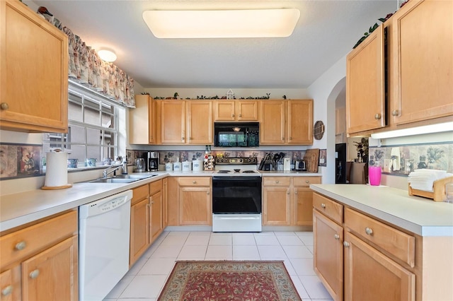 kitchen with sink, light tile patterned floors, light brown cabinetry, and white appliances