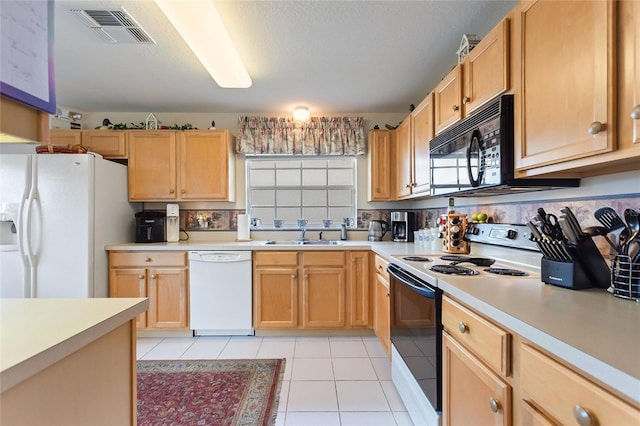 kitchen featuring light tile patterned flooring, sink, white appliances, light brown cabinets, and a textured ceiling