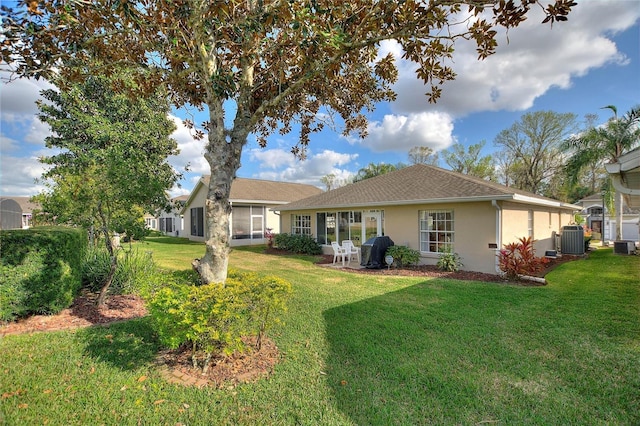 back of house with central AC unit and a lawn