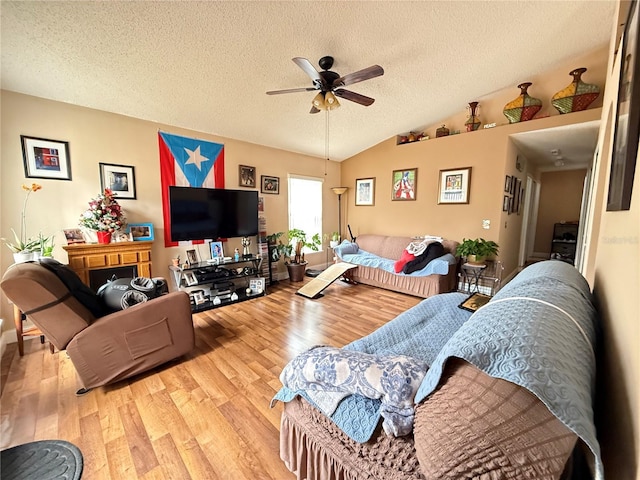 living room featuring ceiling fan, lofted ceiling, a textured ceiling, and light hardwood / wood-style floors