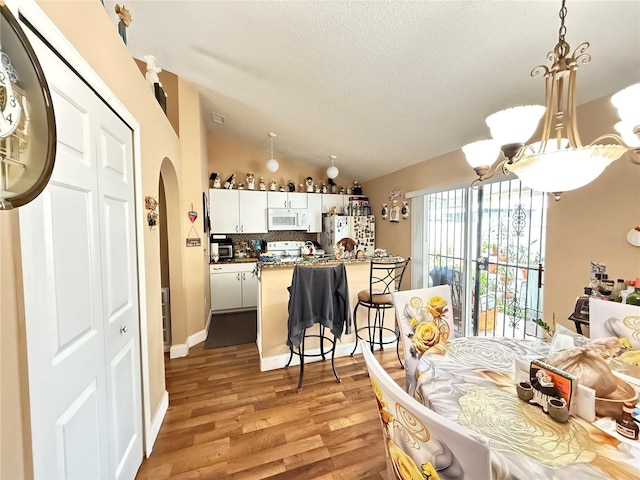 dining space featuring vaulted ceiling, light hardwood / wood-style flooring, and a textured ceiling