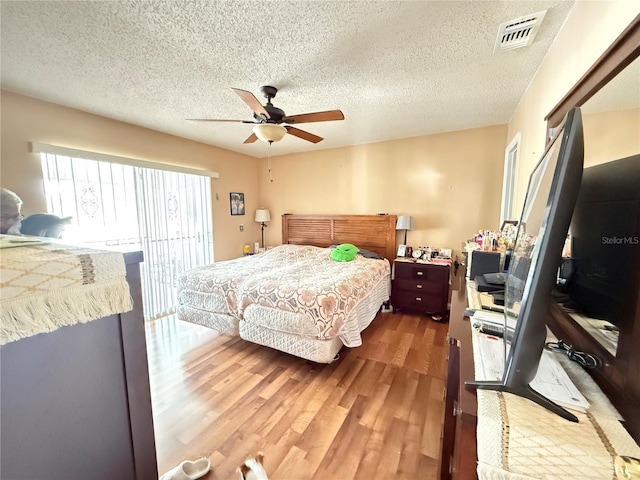 bedroom featuring ceiling fan, wood-type flooring, a textured ceiling, and access to outside