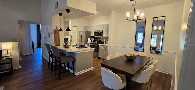 kitchen featuring dark hardwood / wood-style flooring, hanging light fixtures, a breakfast bar area, and stainless steel appliances