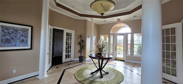 entrance foyer featuring crown molding, a tray ceiling, decorative columns, and light tile patterned floors