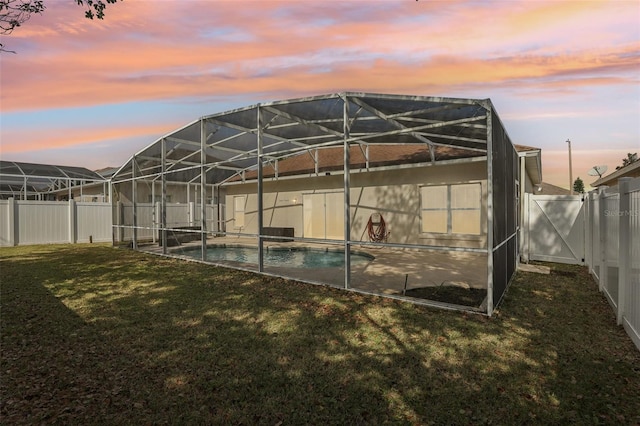 back house at dusk featuring a fenced in pool, a lanai, and a yard