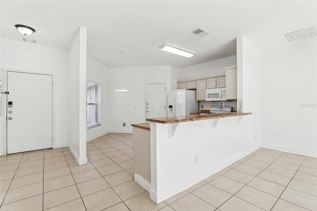 kitchen with light tile patterned floors, white appliances, a kitchen bar, decorative light fixtures, and kitchen peninsula