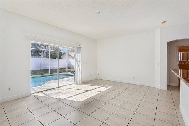 unfurnished room with light tile patterned floors and a textured ceiling