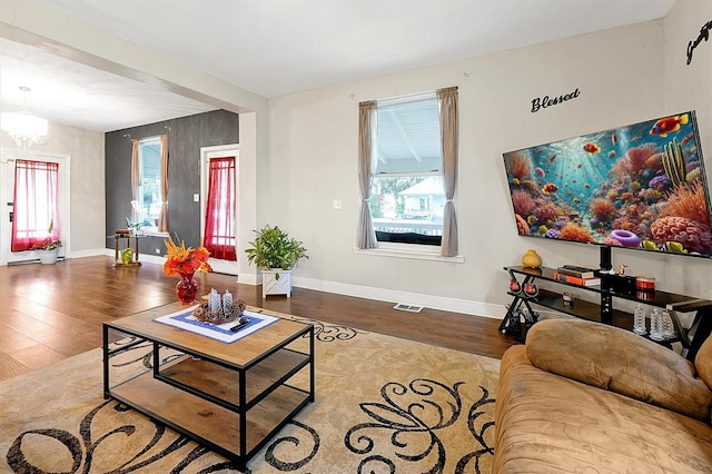 living area featuring visible vents, baseboards, a notable chandelier, and wood finished floors