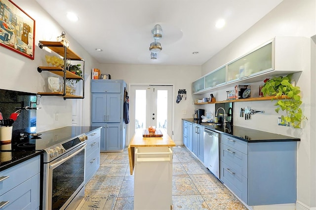 kitchen featuring open shelves, dark countertops, appliances with stainless steel finishes, and a sink