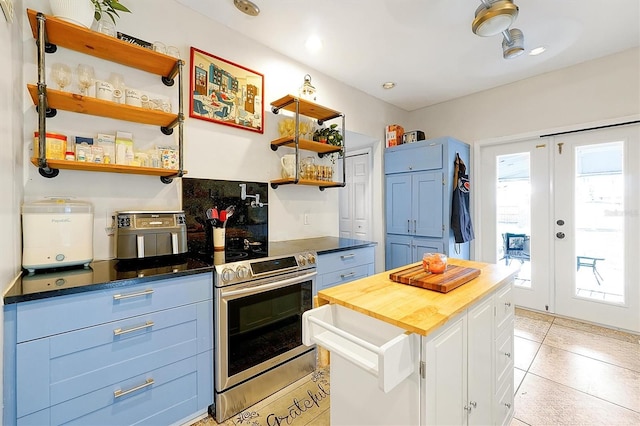 kitchen featuring butcher block counters, stainless steel range with electric cooktop, white cabinetry, blue cabinets, and open shelves