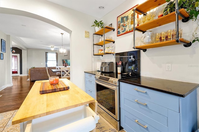 kitchen featuring open shelves, arched walkways, butcher block countertops, stainless steel range with electric stovetop, and open floor plan