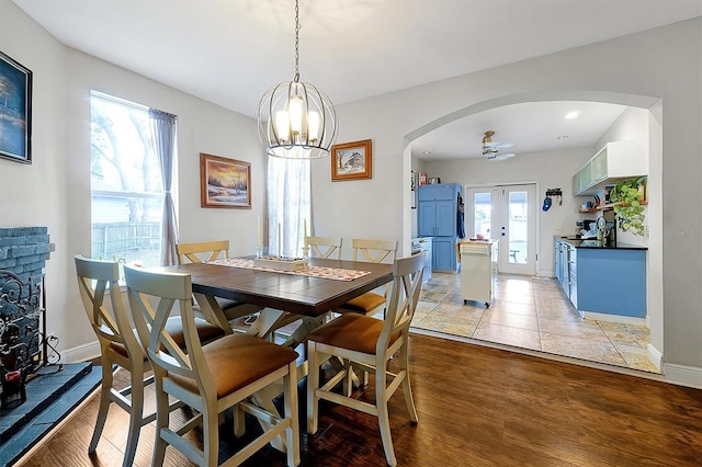 dining space with arched walkways, french doors, light wood-type flooring, and baseboards