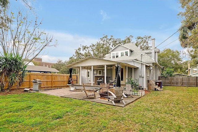 rear view of property with a patio, a lawn, a fenced backyard, and a chimney