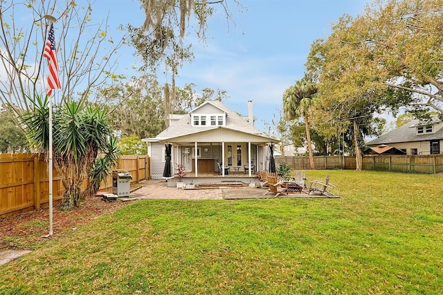 rear view of property with a patio, a lawn, a fenced backyard, and an outdoor fire pit