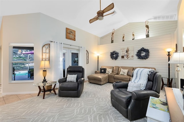 tiled living room with high vaulted ceiling, wooden walls, and ceiling fan