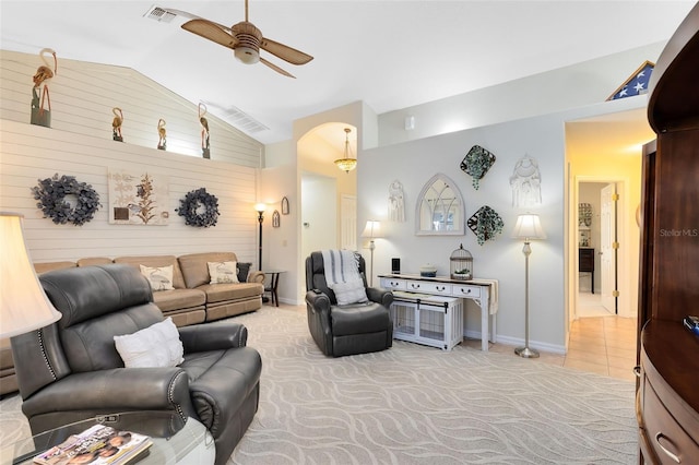 living room featuring lofted ceiling, light carpet, ceiling fan, and wood walls