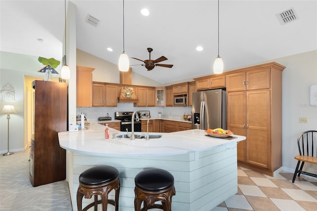 kitchen featuring sink, a breakfast bar, appliances with stainless steel finishes, vaulted ceiling, and kitchen peninsula