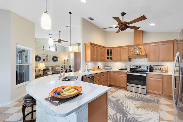 kitchen with pendant lighting, sink, ceiling fan, appliances with stainless steel finishes, and a kitchen breakfast bar