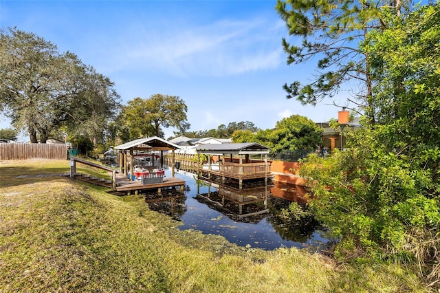 dock area featuring a gazebo, a water view, and a lawn