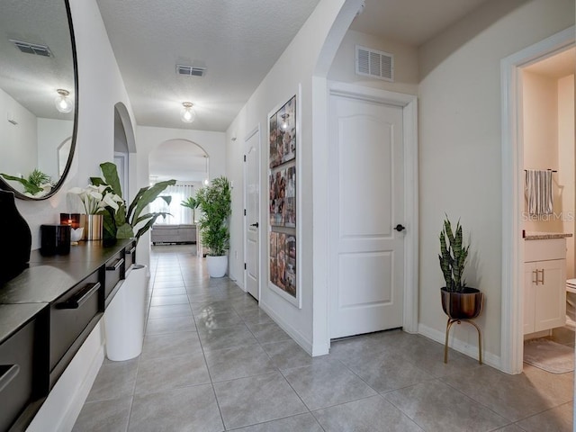 corridor featuring light tile patterned floors and a textured ceiling