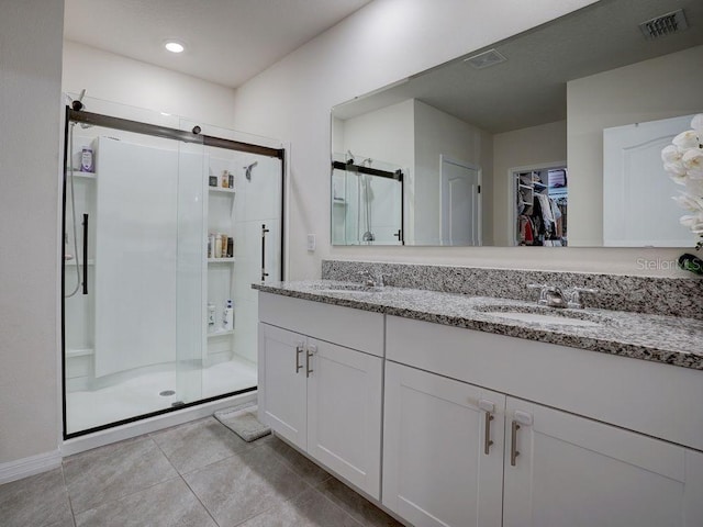 bathroom with walk in shower, vanity, and tile patterned flooring