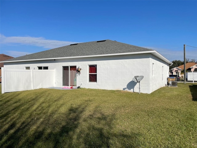 rear view of house featuring a lawn and central air condition unit