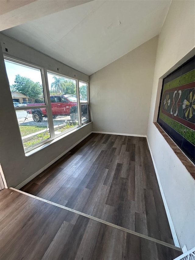 interior space with baseboards, wood finished floors, and lofted ceiling