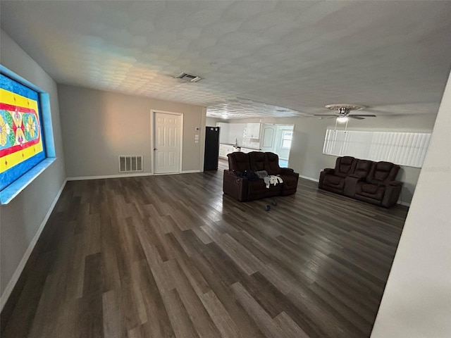 living room featuring visible vents, dark wood-style flooring, and baseboards