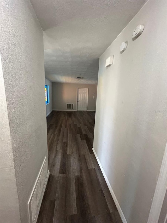 corridor featuring visible vents, baseboards, and wood finished floors