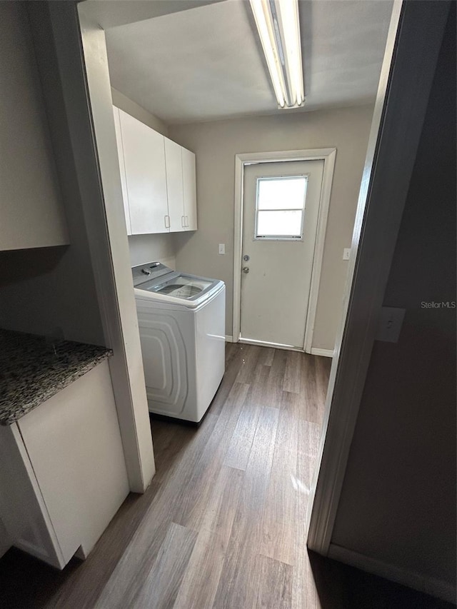 clothes washing area with wood finished floors, cabinet space, and washer / dryer