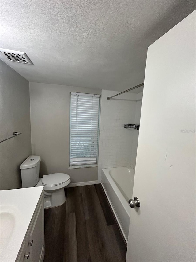 bathroom with vanity, a textured ceiling, toilet, visible vents, and wood finished floors