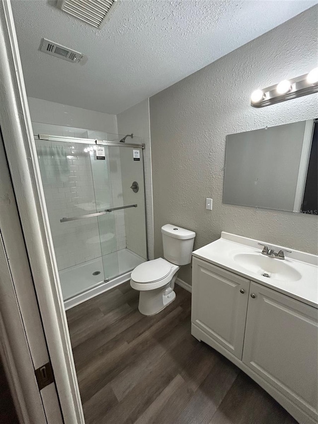 bathroom with visible vents, a textured wall, a textured ceiling, a shower stall, and wood finished floors