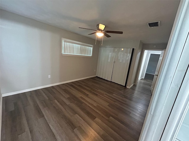 unfurnished bedroom featuring dark wood-type flooring, visible vents, baseboards, and a ceiling fan