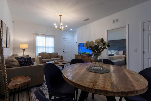 dining area with hardwood / wood-style flooring, a textured ceiling, and an inviting chandelier