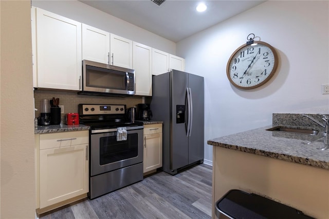 kitchen with stainless steel appliances, dark wood-type flooring, white cabinets, and backsplash