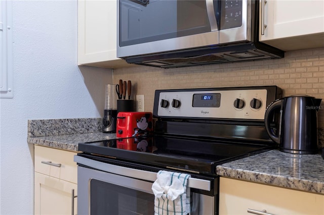 kitchen with tasteful backsplash, stone counters, white cabinets, and appliances with stainless steel finishes