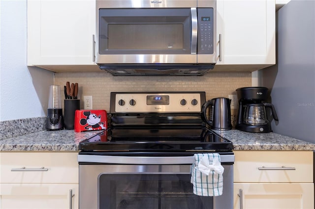 kitchen with light stone countertops, decorative backsplash, stainless steel appliances, and white cabinets