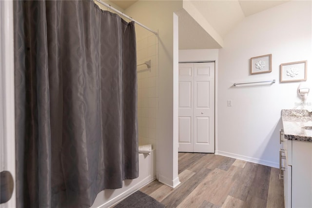 bathroom featuring lofted ceiling, hardwood / wood-style floors, vanity, and shower / tub combo