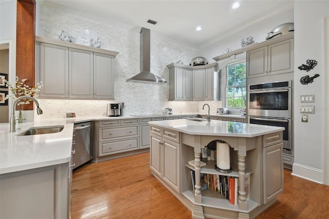 kitchen with stainless steel appliances, a kitchen island, gray cabinets, and wall chimney exhaust hood